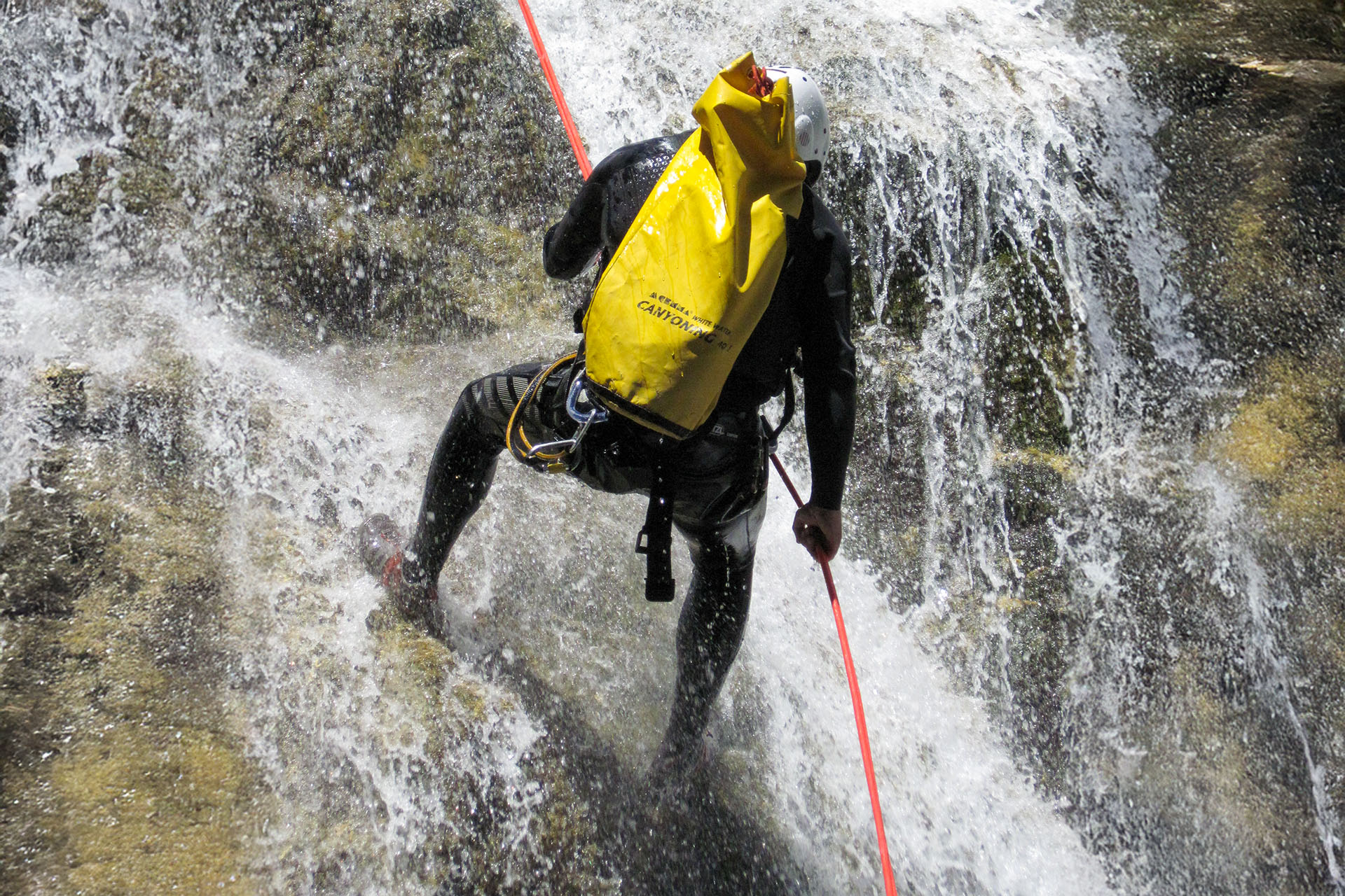 Canyoning in een waterval in de Franse Alpen met touw en wetsuit